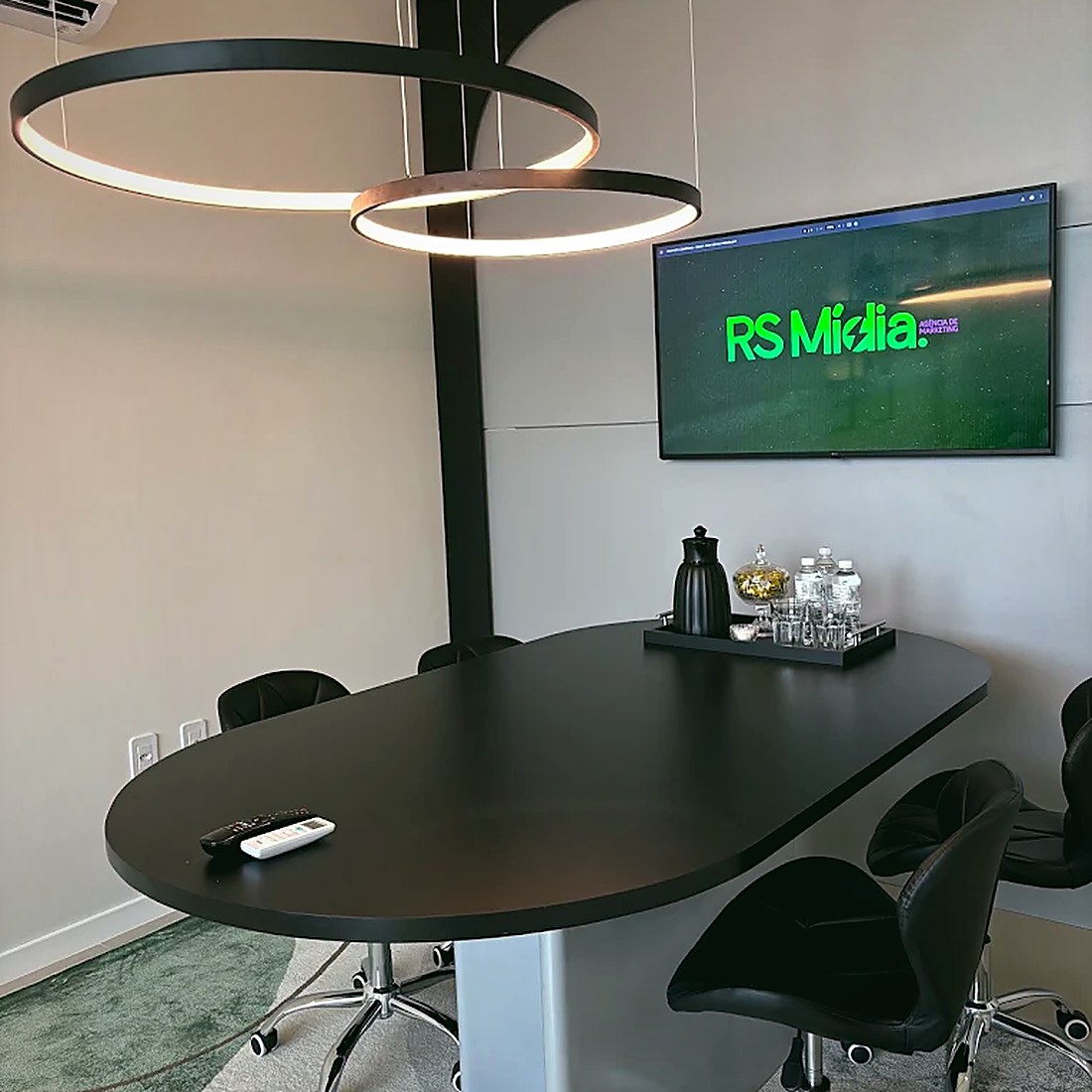 Sala de reunião da RS Mídia com mesa oval e televisor
